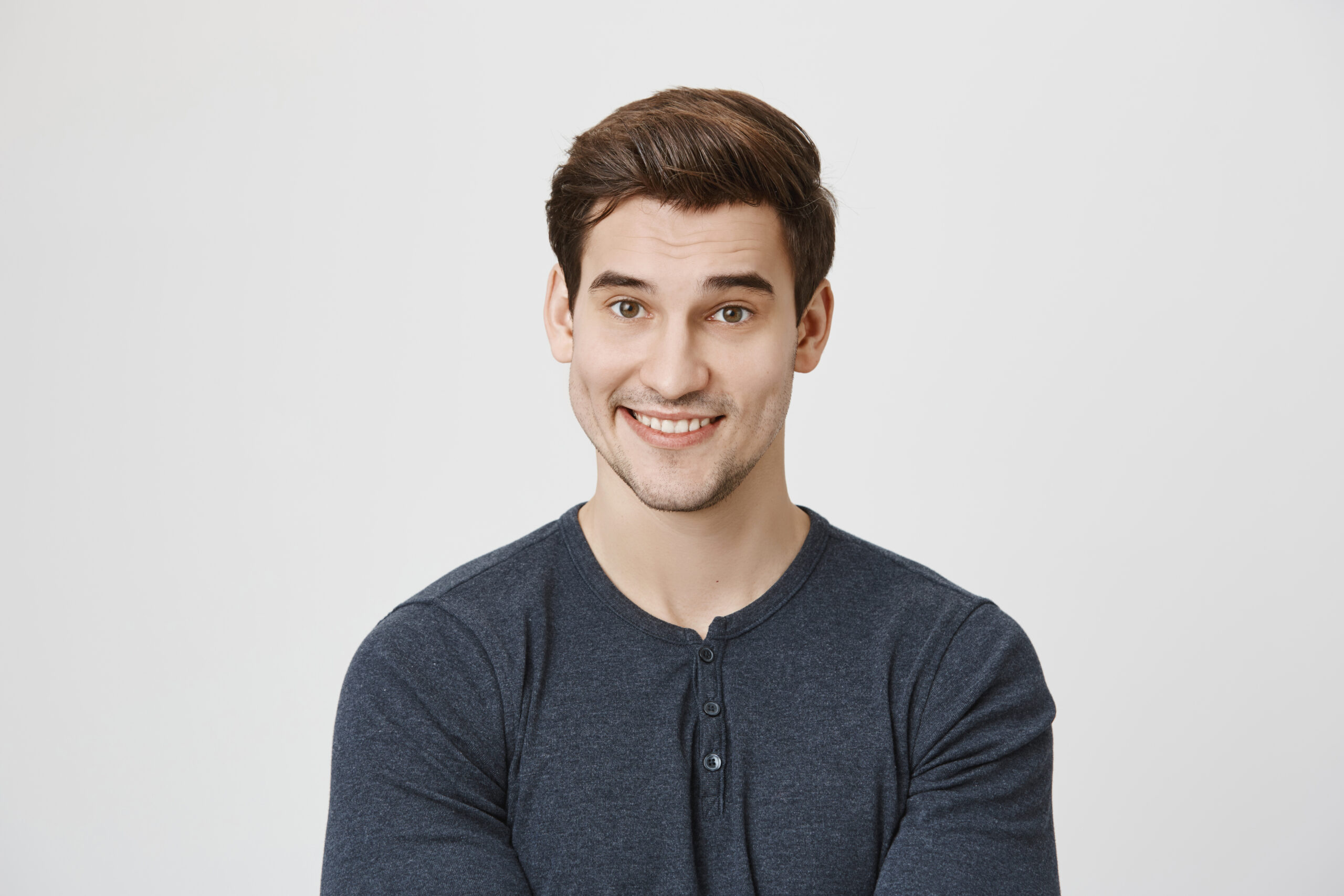 waist up portrait of caucasian handsome attractive young male with dark hair and stubble in casual clothes, pleased to hear praising words from his employer. positive emotions and face expression